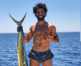 Photo: Liverpool's Mo Salah catches a fish that's nearly as tall as him