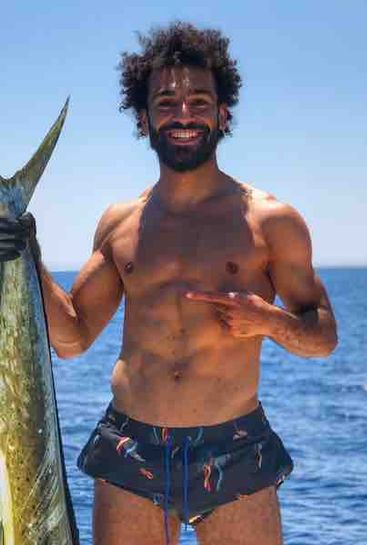 Photo: Liverpool's Mo Salah catches a fish that's nearly as tall as him
